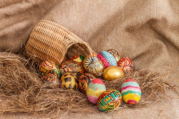 Barevný malovaný velikonoční vajíčko v proutěný koš na seno — Stock fotografie