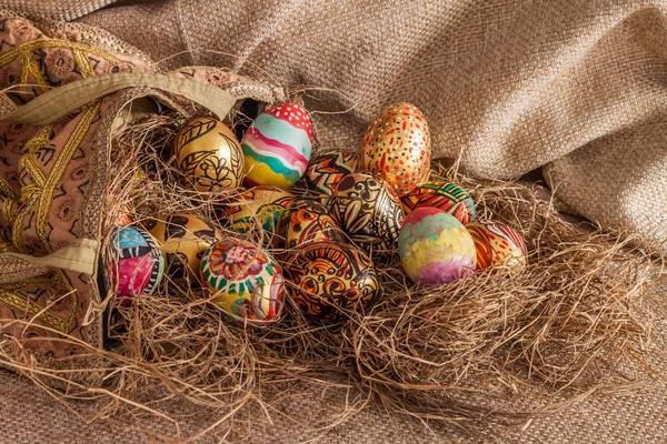 Kumaş çanta saman üzerinde renkli boyalı Paskalya yortusu yumurta — Stok fotoğraf