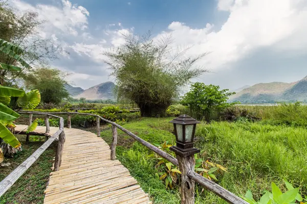 Puente de bambú cerca del embalse con vista a la montaña y al cielo — Foto de Stock