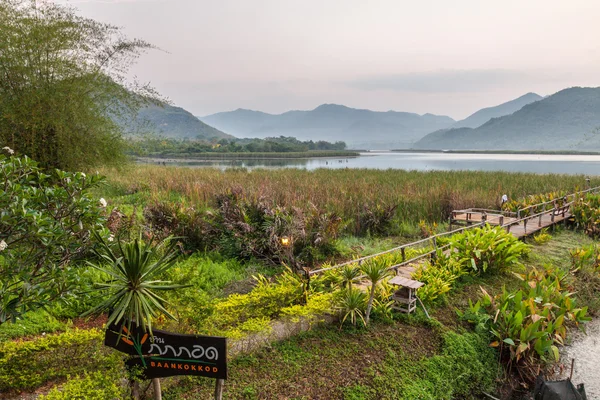 Ponte de bambu perto do reservatório com vista para a montanha e o céu — Fotografia de Stock