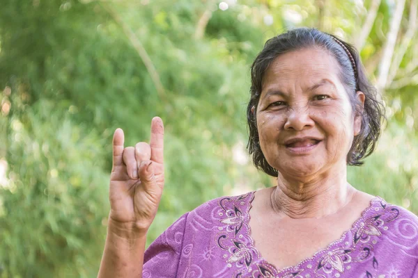 Mulher tailandesa velha sorrindo e disposto a mostrar Eu te amo sinal de mão — Fotografia de Stock