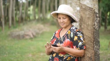 60 yaşında Taylandlı kadın Smartphone kullanırken gülümseyen