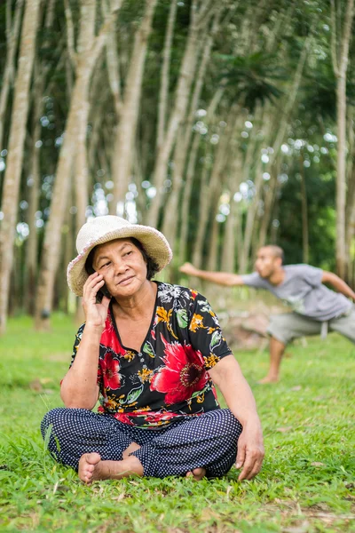 Velha Mulher Asiática Usando Telefone Celular Jardim Enquanto Homem Jogando — Fotografia de Stock