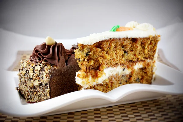 Rijke dubbele chocolade cheesecake met amandel segmenten en zoete wortel taart segmenten — Stockfoto