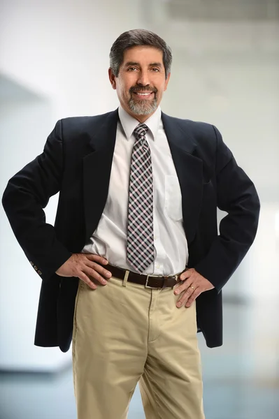 Businessman with hands on hips smiling — Stock Photo, Image