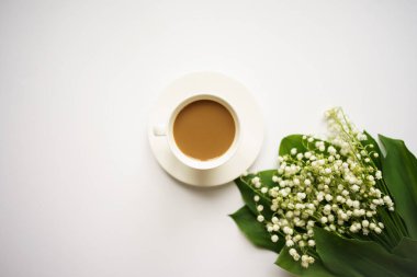 Sütlü kahve ve beyaz arka planda vadi zambakları buketi.