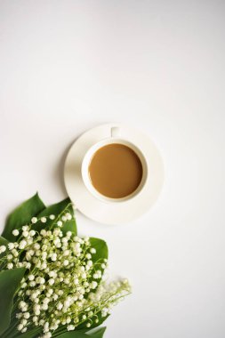 Sütlü kahve ve beyaz arka planda vadi zambakları buketi.