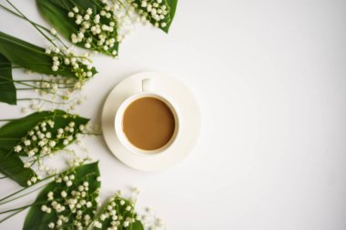 Sütlü kahve ve beyaz arka planda vadi zambakları buketi.