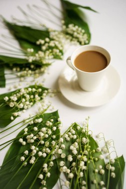 Sütlü kahve ve beyaz arka planda vadi zambakları buketi.