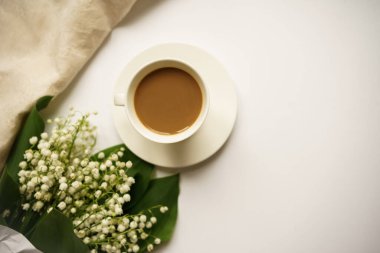 Sütlü kahve ve beyaz arka planda vadi zambakları buketi.