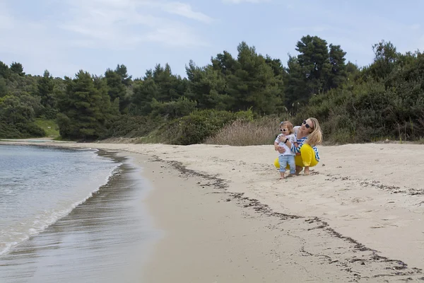 Madre e la sua figlioletta passeggiando lungo una spiaggia . — Foto Stock