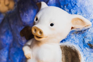 Kanatlı domuz kilden yapılmış ve mavi gökyüzü arka plan duvarına boyanmış..