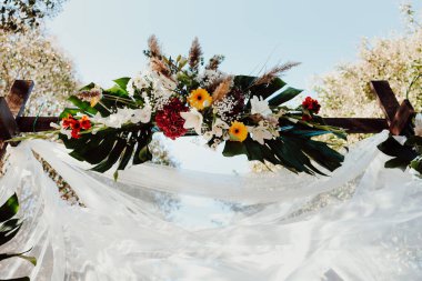 Çiçek aranjmanları ve ipek kumaşlarla süslenmiş bir düğünde..