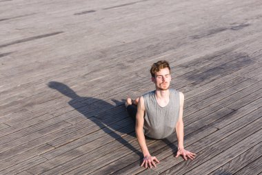 Genç adam şehrin stresinden kurtulmak ve egzersiz yapmak için yoga yapıyor..