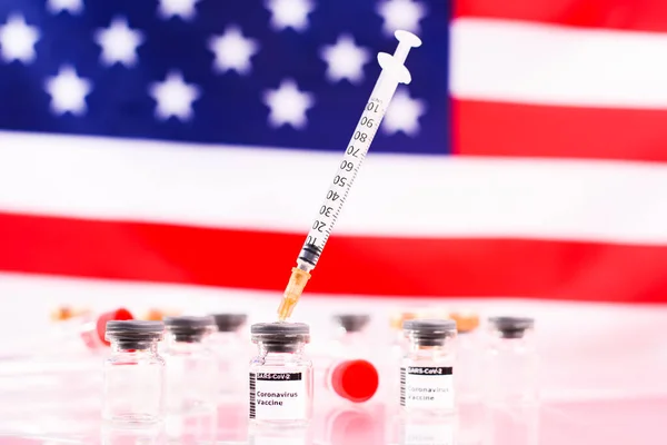 集中力のないアメリカ国旗の前で注射器付きのワクチンのついた医療用バイアル — ストック写真