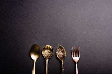 Siyah arka planda geçmişe dönük lüks çatal bıçak takımı, temiz kaşıklar ve çatallar..