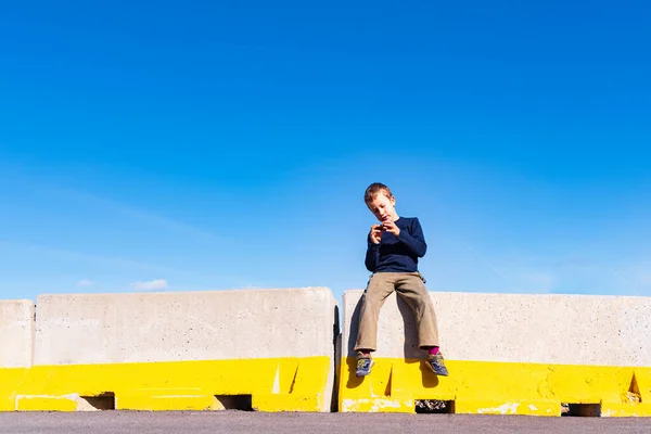 A child play on some construction barriers running into danger, isolated blue background.