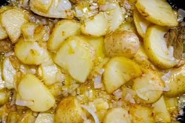 Patates ve sarımsaktan yapılmış tipik bir İspanyol yemeği, tavada zeytinyağıyla kızartılmış, yukarıdan görülüyor.