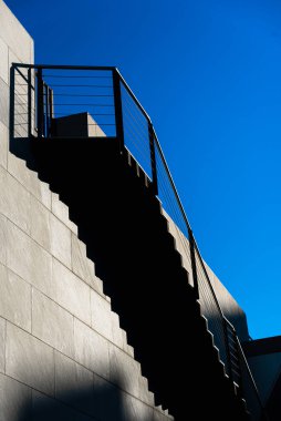 Modern taş merdivenlerin üst basamaklarında gölgeler olan minimalist bir duvar..