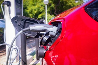 Kırmızı araba ücretsiz bir kamu istasyonunda lityum elektrik pillerini şarj ediyor..