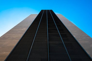 Güç perspektifi olan sembolik yüksek bina, mavi gökyüzüne doğru minimalist yapı, çağdaş arkaplanlar için simetrik tasarım.