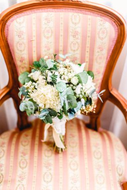 Kurumuş çiçeklerden oluşan güzel ve narin bir gelin buketi zarif bir sandalyede dinleniyor..