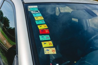 Bir arabanın vitrinindeki renkli ITV etiketleri denetim tarihleri ve ayları gösterir.