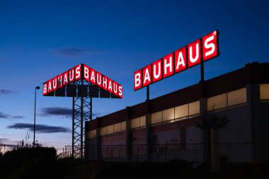 Bir nalbur dükkanının aydınlık tabelaları alacakaranlıkta karanlık gökyüzüne karşı duruyor..