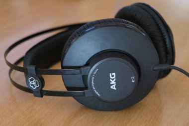 Kaliteli kulaklıklar, rahat bir çalışma alanındaki ahşap bir masanın üzerinde duruyor, ses tasarımı vurgulanıyor..