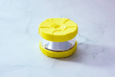 Yol güvenliğinde kullanılmak üzere bir yüzeye sarı bir trafik uyarı feneri yerleştirildi. Arka plan hafifçe bulanık, fenere odaklanmamızı sağlıyor..