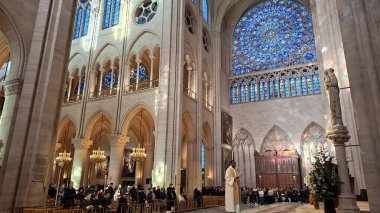 Siyah bir rahip büyük bir kilisede ayine önderlik ediyor. Alanda çarpıcı vitray pencereler ve ahşap sandalyelerde oturan bir cemaat yer alıyor..