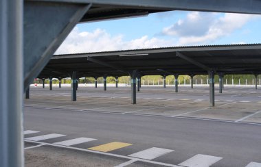 Büyük, boş bir süpermarket otoparkında gölgeli pergolalar var. Bölge park alanlarıyla iyi organize edilmiş ve çevreyi net bir şekilde görebiliyoruz..