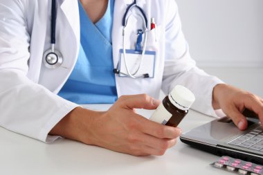 Masada oturan ve hapları ile şişe tutan erkek doktor