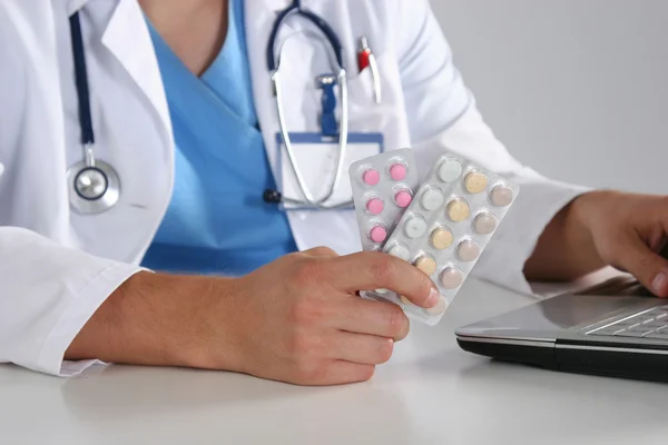 Мужчина-врач сидит за столом и держит таблетки — стоковое фото