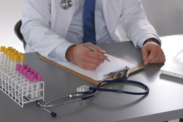 Male doctor write on the desk with test tube
