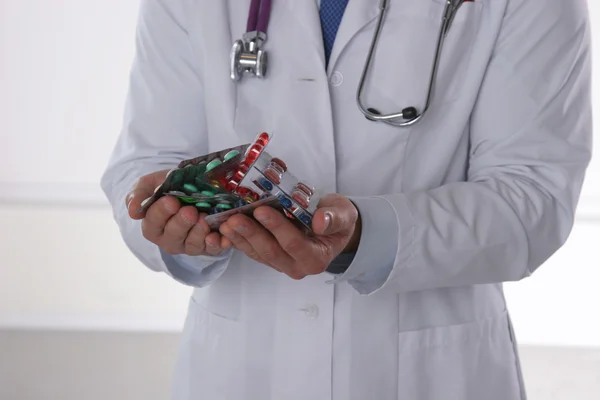 Médico masculino segurando uma pilha de muitas pílulas diferentes — Fotografia de Stock