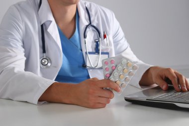 Masada oturan ve şişe tutan erkek doktor