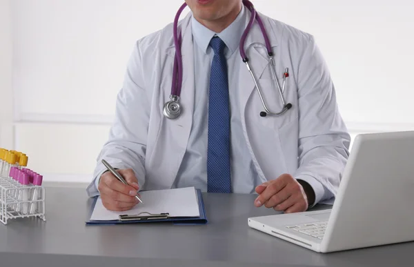Médico masculino escrever na mesa com tubo de ensaio — Fotografia de Stock