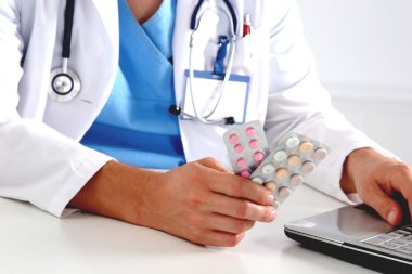 Masada oturan ve şişe tutan erkek doktor