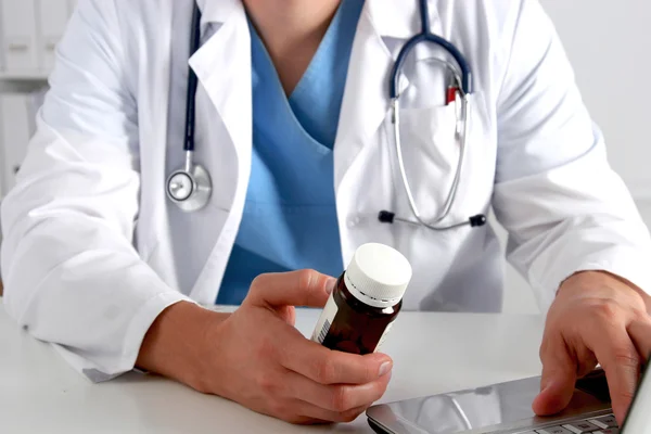 Masada oturan ve şişe tutan erkek doktor