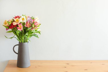 Tahta bir masadaki çimento vazoda renkli çiçekler.