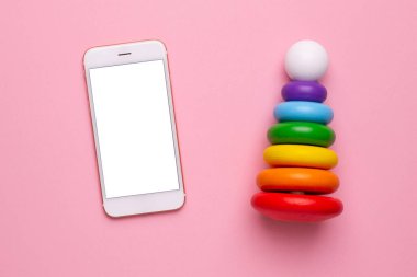 Cep telefonu ve pembe arka plan manzaralı renkli çocuk piramidi.