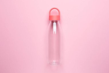 Pembe arka planda şeffaf su şişesi. Koşu ve spor manzarası için.