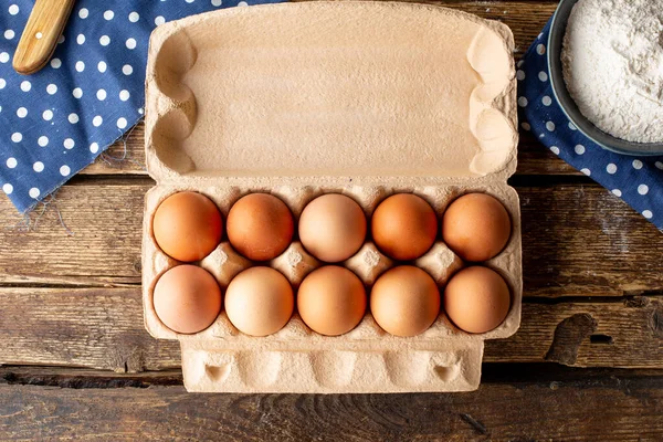 Brown chicken eggs packaged on a wooden background, cooking at home top view