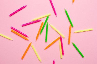 Doğum günü pastası için renkli mumlar. Telif alanı üst görünümü olan pembe bir arkaplan üzerinde.