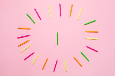 Doğum günü pastası çerçevesi için renkli mumlar. Telif alanı üst görünümü olan pembe bir arkaplan üzerinde.