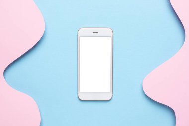 Cep telefonu ve soyut kağıt, pembe arkaplan, pastel renkler ve teknoloji üst görünümü üzerindeki mavi dalgaları keser