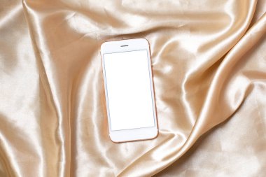 Düz konsept kadınsı ışık arkaplanı Bej ipek üzerinde cep telefonu ile .Beyaz ekran fotokopi alanı üst görünümü.