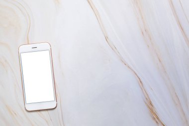 Boş beyaz ekran ve mermer masanın üzerinde kopyalama alanı olan düz bir akıllı telefon. Arkaplanınızı yerleştirmek için Zarif Tasarım, Tasarımınız ve ürünlerinizin üst görünümü için şablon oluşturun