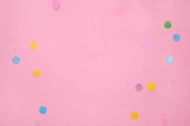 Pembe arkaplanda üst görünümü olan renkli konfeti